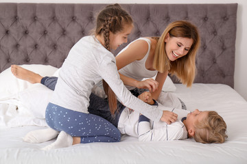 Woman playing with children in bedroom. Happy family