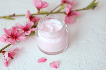 Fototapeta na wymiar Jar of cream and blossoming branch on table
