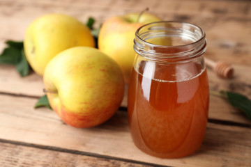 Jar of honey and apples on wooden table