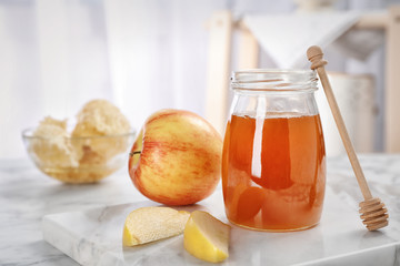 Jar of honey, apples and dipper on marble table