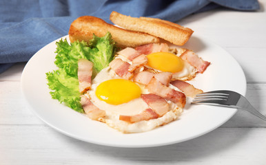Fried eggs with bacon and toasted bread on plate served for breakfast