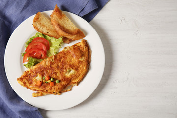 Omelet with vegetables on plate served for breakfast, top view