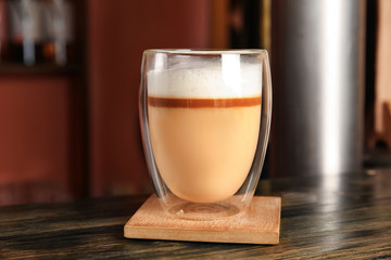 Glass with delicious latte on wooden table