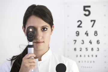 Portrait Augenärztin mit eingeschaltetem Ophthalmoskop und Lichtstrahlen