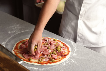 Obraz na płótnie Canvas Chef preparing pizza on table in restaurant kitchen