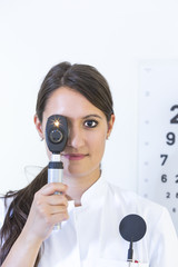 Portrait Augenärztin mit eingeschaltetem Ophthalmoskop und Lichtstrahlen