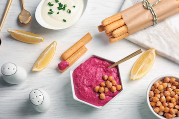 Fototapeta na wymiar Flat lay composition with bowl of tasty beet hummus, bread sticks and chickpea on light table