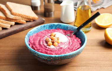 Bowl with tasty creamy beet hummus on wooden table