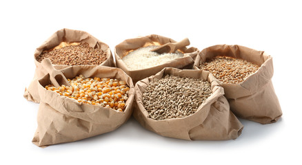 Paper bags with different types of grains and cereals on white background