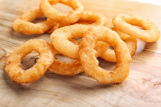 Fried onion rings on wooden background, closeup