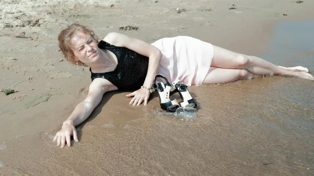 drunk woman lies on the beach with a glass of wine after a party