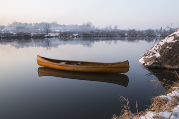 new Canoe floating on the calm water in winter sunset