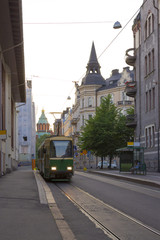 Obraz na płótnie Canvas The evening tram rides along the historic street near the Assumption Cathedral in Helsinki in Finland on a summer evening.