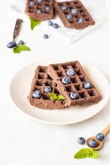 Chocolate brussels waffles with fresh blueberries and mint on a plate.