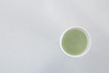 white paper coffee cup isolated on white with green juice top view.