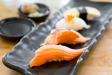 Close up of japanese cuisines nigiri sushi set on black plate served with wasabi, soy sauce in japanese food restaurant.