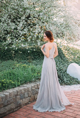 Red-haired girl in a modest, gray dress in rustic style. Portrait of the bride on the background of...
