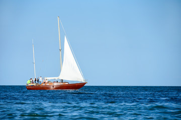 A yacht with tourists sails on the blue sea