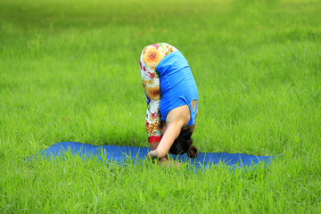 Fototapeta na wymiar A woman is practicing yoga on the grass