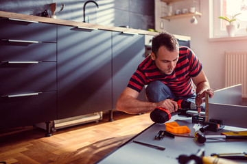 Woman building kitchen and using a cordless drill