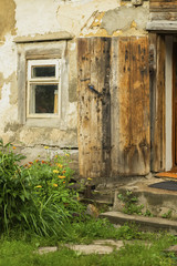 Wall of an old farm building. Natural texture. Specially preserved rural wooden house for agriturism, window, open door, country vintage house. Summer, flowers in yard