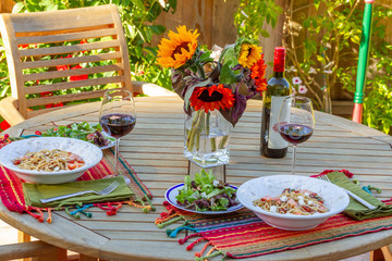 Alfresco Dining on Teak Dining Set With Sunflowers, Pasta Bowls, Salad Plates, Placemats, Red Wine, Napkins, Wine Bottle