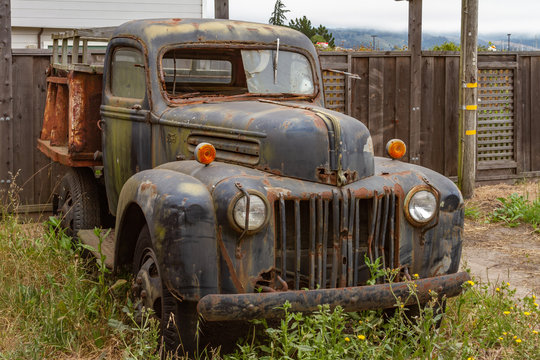 Ancient Rusting Old Pickup Truck in Front of a Wooden Fence