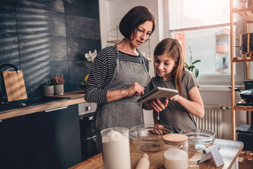 Mother and daughter searching apple pie recipe on the tablet