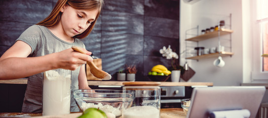 Girl adding flour into mixing bowl