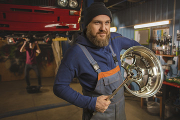 Obraz na płótnie Canvas A bearded car mechanic works in the garage. Car mechanic in the garage. Hard work.