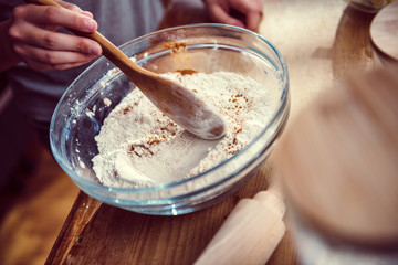 Girl mixing flour and cinnamon into mixing bowl