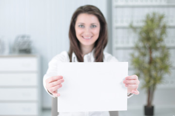 business woman showing blank sheet,sitting behind a Desk