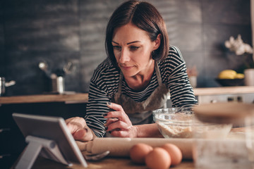 Woman searching apple pie recipe on the tablet - obrazy, fototapety, plakaty