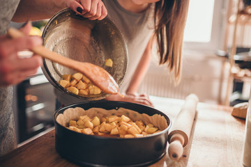 Woman pouring apple filling into baking pan