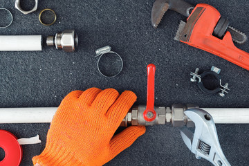 Hands repairing in gloves the plumbing pipes  with a spanner