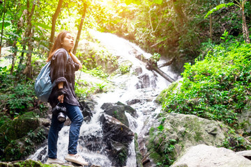 Traveler young woman photographing with camera near the waterfall outdoor