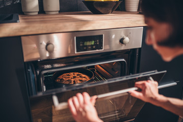 Woman checking apple pie in oven - obrazy, fototapety, plakaty