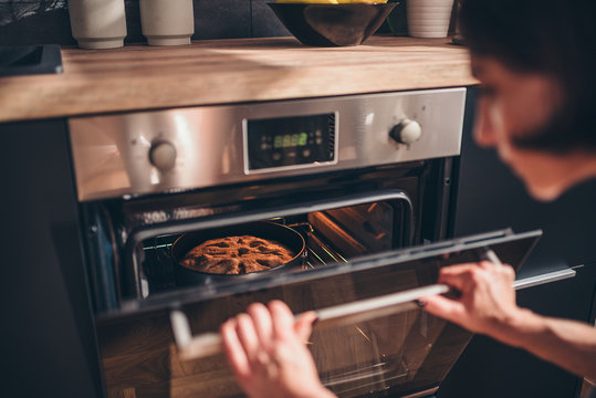 Woman checking apple pie in oven