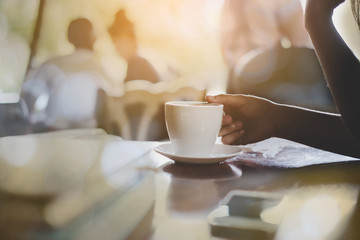Close up woman hands holding a cup of coffee over wooden table