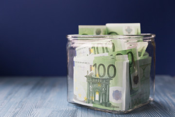 Fresh crisp euro bills in a square glass jar