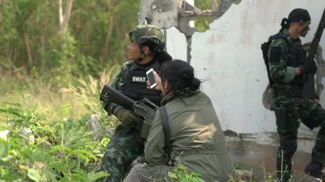 Soldier fieldwork interview with presswoman. Reporter unsafe area. Soldier holding gun weapon and waring armor uniform.
