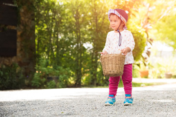 Fototapeta premium Happy little girl running with basket the garden farm. Summer activities for kids.