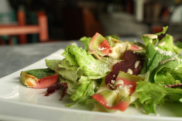 Green salad with Prosciutto and dressing  on a white plate, close up, restaurant,