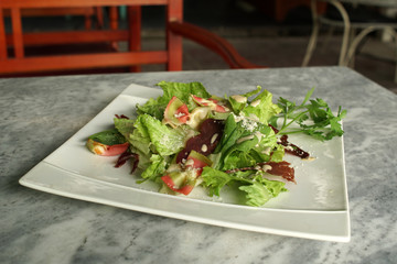 Green salad with Prosciutto and dressing  on a white plate, close up, restaurant,