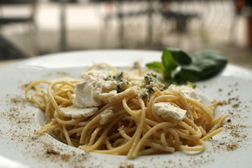 Spaghetti with basil & white cheese on top, close up