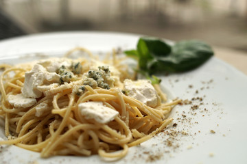 Spaghetti with basil & white cheese on top, close up