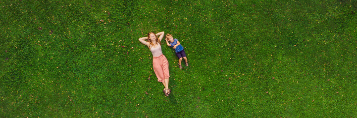 Mom and son are lying on the grass in the park, photos from the drone, quadracopter BANNER long format