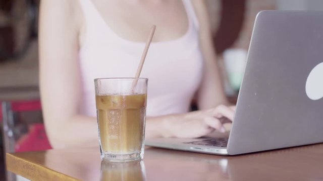 Young woman working on a laptop computer and drinking coffee
