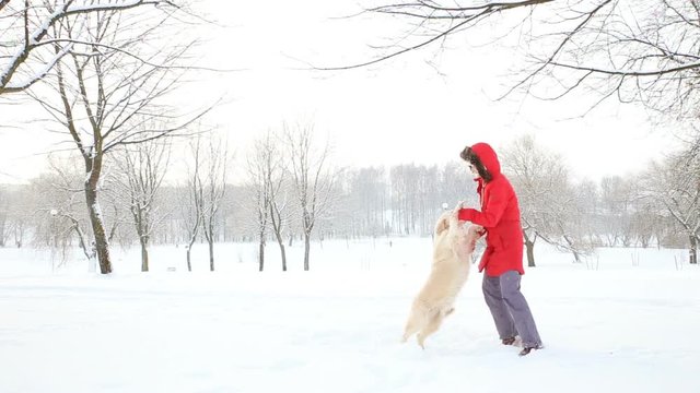 love for pets - a cheerful woman dances and has fun with her dog in a winter snow-covered park