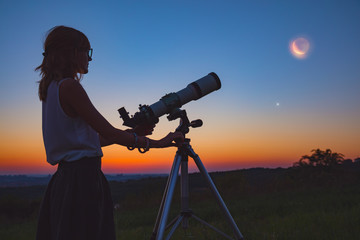 Girl looking at lunar eclipse through a telescope. My astronomy work.